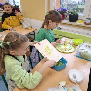 Dziewczynki z klasy 3 b w trakcie krojenia zielonych owoców. Kliknięcie na zdjęcie spowoduje jego powiększenie do rozmiaru oryginalnego.