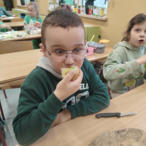 Chłopiec z klasy 1 a w trakcie jedzenia przygotowanej przez siebie kanapki z zielonymi warzywami. Kliknięcie na zdjęcie spowoduje jego powiększenie do rozmiaru oryginalnego.