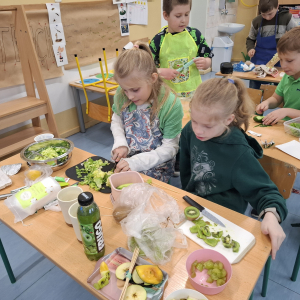 Grupka dzieci z klasy 3 b w trakcie sporządzania posiłków z zielonych owoców i warzyw. Kliknięcie na zdjęcie spowoduje jego powiększenie do rozmiaru oryginalnego.