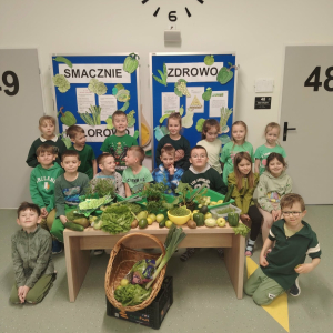 Klasa 1 a ubrana na zielono, przed dziećmi stół z zielonymi owocami, warzywami oraz ziołami. Kliknięcie na zdjęcie spowoduje jego powiększenie do rozmiaru oryginalnego.