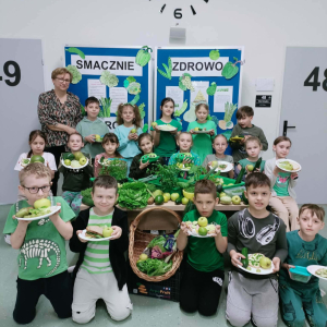 Uczniowie klasy 2 b wraz z wychowawczynią prezentują przygotowane kanapki z okazji "Dnia na Zielono". Kliknięcie na zdjęcie spowoduje jego powiększenie do rozmiaru oryginalnego.
