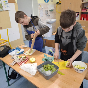 Uczniowie klasy 3 b przygotowują sałatki owocowe z zielonych owoców. Kliknięcie na zdjęcie spowoduje jego powiększenie do rozmiaru oryginalnego.