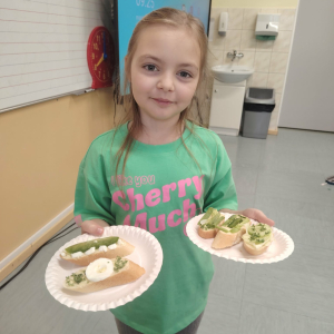 Pierwszoklasistka prezentuje przygotowane przez siebie kanapki. Kliknięcie na zdjęcie spowoduje jego powiększenie do rozmiaru oryginalnego.