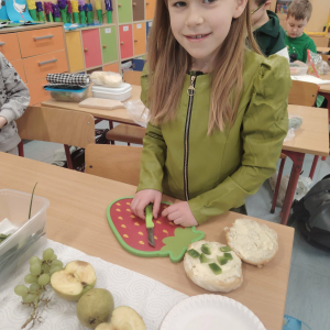 Uczennica klasy 1 a w trakcie przygotowywania kanapek w ramach dnia na zielono. Kliknięcie na zdjęcie spowoduje jego powiększenie do rozmiaru oryginalnego.