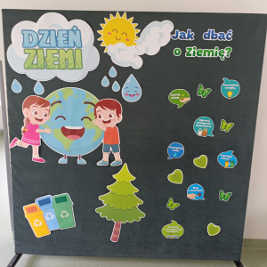 Sztaluga z dekoracją przygotowaną z okazji Dnia Ziemi: dzieci obejmujące Ziemię, chmury, pojemniki na śmieci, krople oraz napisy. Kliknięcie na zdjęcie spowoduje jego powiększenie do rozmiaru oryginalnego.