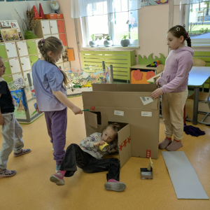 Dzień bez zabawek: trzy dziewczynki w trakcie zabawy w kartonowym domku wykonanym samodzielnie. Kliknięcie na zdjęcie spowoduje jego powiększenie do rozmiaru oryginalnego.