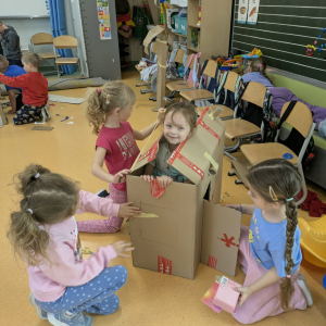 Grupka dziewczynek z przedszkola bawi się w kartonowym domku przygotowanym przez siebie. Kliknięcie na zdjęcie spowoduje jego powiększenie do rozmiaru oryginalnego.