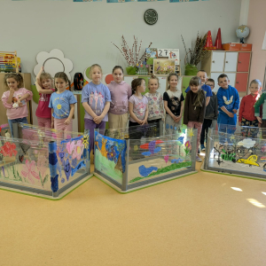 Przedszkolaki prezentują swoje prace: pomalowane folie przyczepione do odwróconych stolików. Kliknięcie na zdjęcie spowoduje jego powiększenie do rozmiaru oryginalnego.