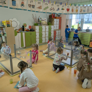 Sześciolatki malują farbami na foliach zamocowanych na odwróconych stolikach. Kliknięcie na zdjęcie spowoduje jego powiększenie do rozmiaru oryginalnego.