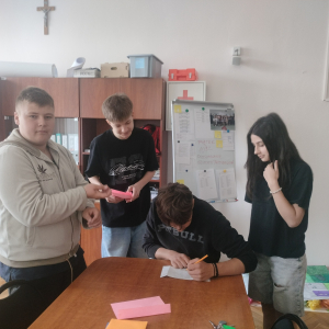 Grupka uczniów z klasy 8 b w pokoju nauczycielskim rozwiązuje zadania przygotowane w ramach gry terenowej.  Kliknięcie na zdjęcie spowoduje jego powiększenie do rozmiaru oryginalnego.