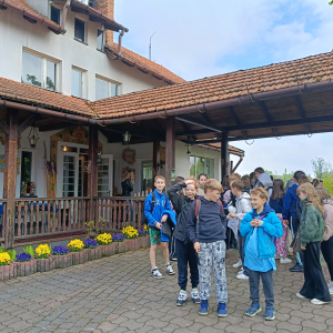 Uczestnicy wycieczki zgromadzeni przed domem w Zagrodzie Edukacyjnej "Pszczółka". Kliknięcie na zdjęcie spowoduje jego powiększenie do rozmiaru oryginalnego.