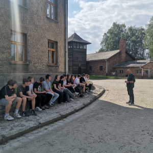 Uczniowie siedzą na krawężniki przy jednym z budynków Nazistowskiego Obozu Zagłady w Oświęcimiu. Kliknięcie na zdjęcie spowoduje jego powiększenie do oryginalnego rozmiaru.