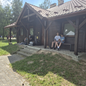 Siódmoklasiści siedzą pod domkiem w czasie pobytu w Borku. Kliknięcie na zdjęcie spowoduje jego powiększenie do rozmiaru oryginalnego.