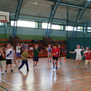 Uczniowie klas 1 biegają po hali gimnastycznej. Dzieci biorą udział w zabawach zorganizowanych z okazji Dnia Dziecka. Kliknięcie na zdjęcie spowoduje jego powiększenie do rozmiaru oryginalnego.