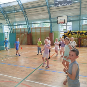 Grupka uczniów z klas 1 bawi się na hali gimnastycznej z okazji Dnia Dziecka. Kliknięcie na zdjęcie spowoduje jego powiększenie do rozmiaru oryginalnego.