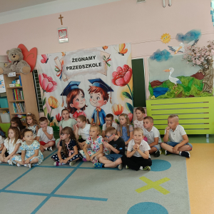 Dzieci z oddziału przedszkolnego zgromadzone na dywanie. Kliknięcie na zdjęcie spowoduje jego powiększenie do rozmiaru oryginalnego.